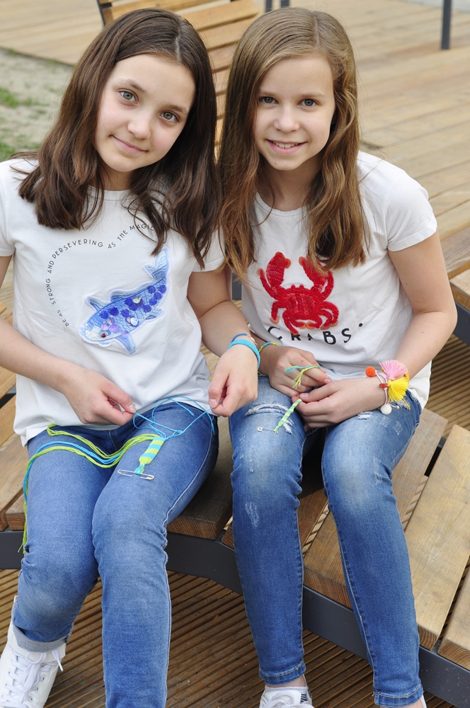 dwie dziewczynki pokazują jak samemu zrobić bransoletkę z muliny